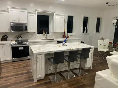 a kitchen with white cabinets and a kitchen island with black chairs at Paradise Pool House in Dania in Dania Beach