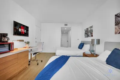 a hotel room with two beds and a desk with a tv at Spectacular Studio Amazing Amenities Bay View in Hallandale Beach