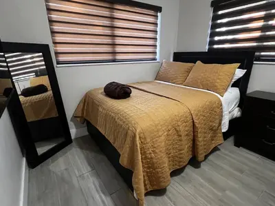 a bedroom with a bed with a yellow blanket and a mirror at Luxurious Westchester Home Near Miami Clinics in Miami