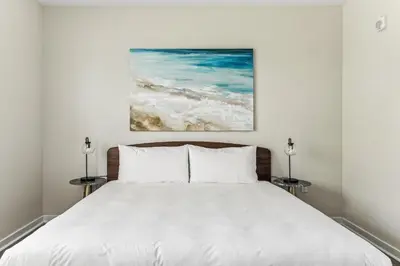 a bedroom with a white bed with a painting on the wall at Kasa Hollywood Fort Lauderdale in Dania Beach