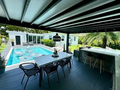 a patio with a table and chairs and a swimming pool at Pura Vida Villa in Miami