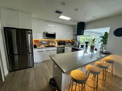 a kitchen with a refrigerator and a counter with stools at Pura Vida Villa in Miami