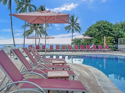 a pool with chairs and umbrellas next to the water at Amazing 3 bedrooms 3 bathrooms Beach Resort 1518 in Miami Beach