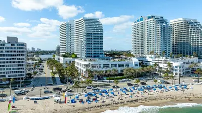 a beach with chairs and umbrellas in front of tall buildings at FLL W Residence Penthouse, AMAZING birds eye views! in Fort Lauderdale