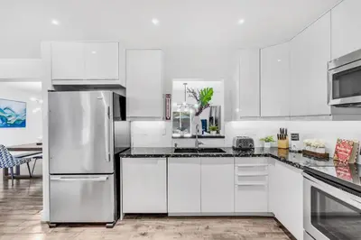 a kitchen with white cabinets and a stainless steel refrigerator at Spacious 5 Bedroom Heated Pool and Hot Tub, 12 minutes to the Beach in Hollywood