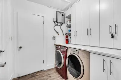 a laundry room with a washing machine and white cabinets at Spacious 5 Bedroom Heated Pool and Hot Tub, 12 minutes to the Beach in Hollywood