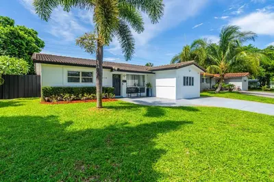 a house with a palm tree in a yard at Spacious 5 Bedroom Heated Pool and Hot Tub, 12 minutes to the Beach in Hollywood