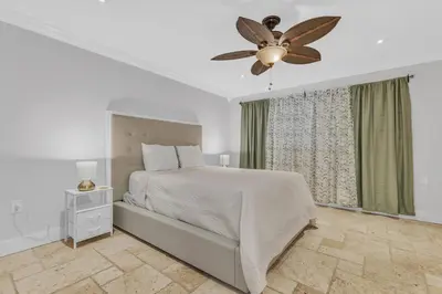 a white bedroom with a bed and a ceiling fan at Tropical Oasis with Heated Pool and BBQ in Tamiami