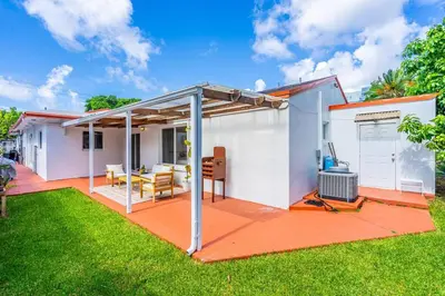 a small white house with a patio and grass at Modern 3 Bedroom GetAway with Parking in Coral Gables in Miami