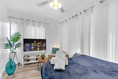 a white bedroom with a blue bed and a tv at Wonderful 6ppl Apt 5 min walking Design District 2 in Miami