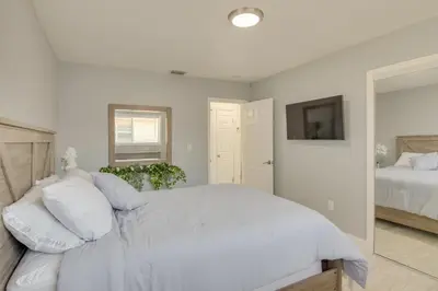 a white bedroom with a large bed and a mirror at Miami Gardens Apt 5 Miles to Hard Rock Stadium in Miami Gardens