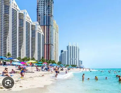 a beach with many people in the water and buildings at Azure North Beach in Miami Beach