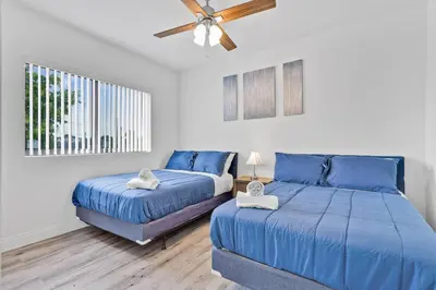a bedroom with two blue beds and a ceiling fan at Magical bright Apt 5min walking Design District apt 5 in Miami