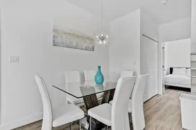 a dining room with a glass table and white chairs at Quiet Bright Apt 5min walking to Design District apt 6 in Miami