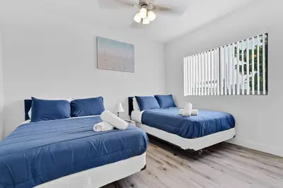 two beds in a white room with blue sheets at Stylish Lux Apt 5 min walking to Design District apt 7 in Miami