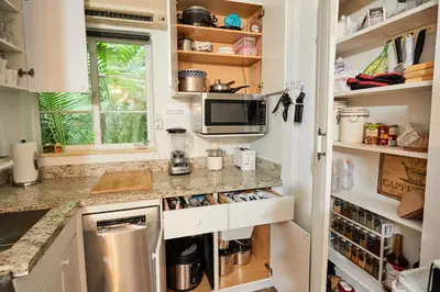 a kitchen with white cabinets and a counter at Miami Pool Cottage, tropical garden paradise in Miami