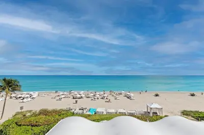 a beach with a crowd of people and the ocean at Ocean View Luxurious Studio Premium Amenities in Sunny Isles Beach