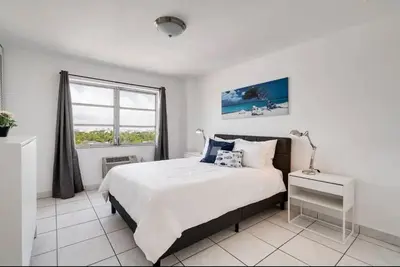 a white bedroom with a large bed and a window at 1106- 1BR & 1BA with Balcony, Stunning City & Ocean Views in Miami Beach