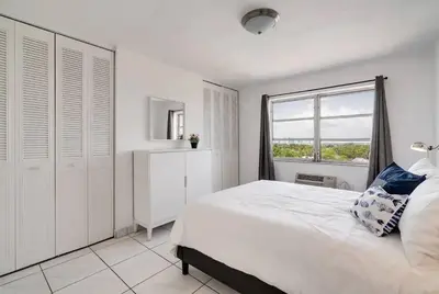 a white bedroom with a large bed and a window at 1106- 1BR & 1BA with Balcony, Stunning City & Ocean Views in Miami Beach