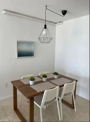 a dining room table with white chairs and a light fixture at 1401- Stylish 1BR& 2BA with Breathtaking Ocean Views in Miami Beach