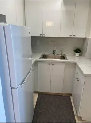 a white kitchen with a sink and a refrigerator at 1401- Stylish 1BR& 2BA with Breathtaking Ocean Views in Miami Beach