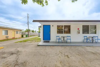 a small white building with blue doors and chairs at 2 Mi to Dtwn Hollywood Vibrant Pet-Friendly Condo in Hallandale Beach