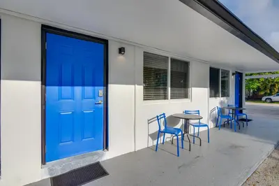 a blue door on a building with chairs and a table at Pet-Friendly Hallandale Beach Condo Near Boardwalk in Hallandale Beach