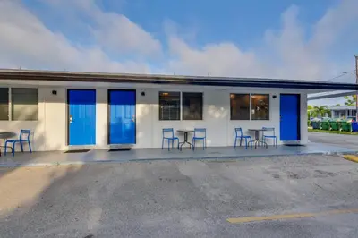 a building with blue doors and chairs in a parking lot at Pet-Friendly Hallandale Beach Condo Near Boardwalk in Hallandale Beach