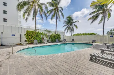 a swimming pool with palm trees and a fence at Cozy Miami Beach Apartment Less Than 1 Mi to Ocean! in Miami Beach