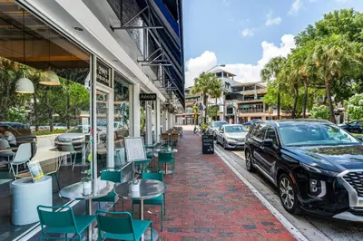 a street with tables and chairs and a car parked on a sidewalk at Renovated Coconut Grove Studio includes Parking in Miami