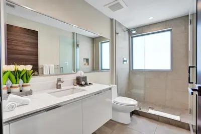 a bathroom with a sink and a toilet and a mirror at Luxury Beach Front Suite with Rooftop Pool in Hollywood