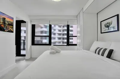 a white bedroom with a large white bed and windows at Ocean View Elegant 2BDR 2BA Condo Beach Access 714 in Miami Beach