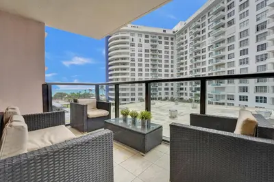 a balcony with wicker furniture and a large building at Cozy Ocean View Condo Beach Service 617 in Miami Beach