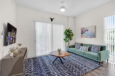 a living room with a green couch and a table at Bright and Airy 2 Bed on Biscayne Blvd with Free Park in Miami