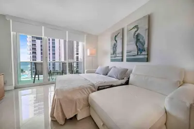 a bedroom with a bed and a couch and windows at Luxe Hollywood Beachfront Condo in Hollywood