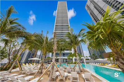 a swimming pool with chairs and a tall building at Modern 1BD & Den With City Views in Miami