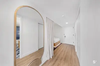 a hallway with a mirror and a bed in a room at Modern 1BD & Den With City Views in Miami