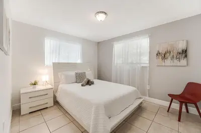 a bedroom with a white bed and a red chair at Stylish 3 Bedroom Miami Retreat Close Brickell in Miami