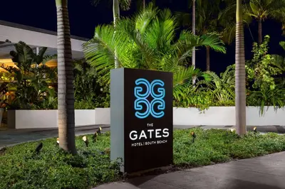 a sign in front of a building with palm trees at The Gates Hotel South Beach in Miami Beach