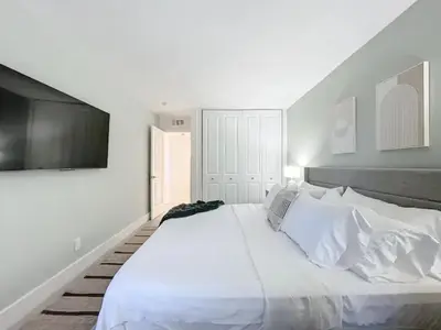 a white bedroom with a large bed and a flat screen tv at Cordova Arms By Rocketstay in Fort Lauderdale