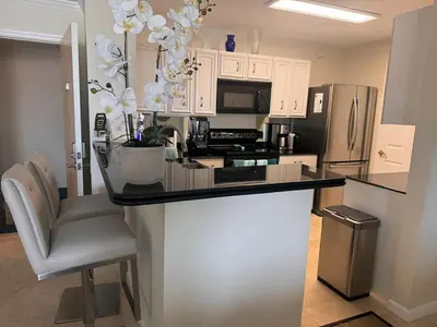 a kitchen with a black counter and a refrigerator at The Costal, stunning water view apartment at Aventura Yacht Club, Miami Florida! in Sun Swept Isles