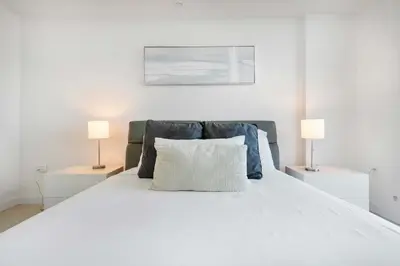 a bedroom with a white bed with two lamps at La Central- CityPlace Doral and across from a Park in Miami
