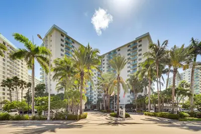 a row of palm trees in front of a building at Hollywood Condo with Beach Access - Walk to Shore! in Hollywood
