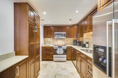 a kitchen with wooden cabinets and a stove top oven at Hollywood Condo with Beach Access - Walk to Shore! in Hollywood