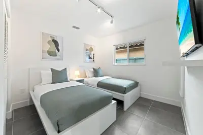 a white bedroom with two beds and a window at Luxurious Family Escape in Hialeah