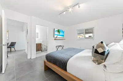 a white bedroom with a bed and a desk at Luxurious Family Escape in Hialeah