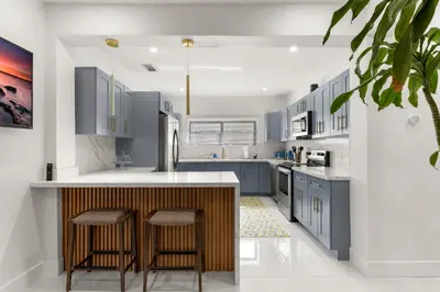 a kitchen with blue cabinets and a island with stools at Charming Home Close to Beaches & Downtown in Miami
