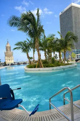 a swimming pool with palm trees and a chair at Magic Miami Penthouse, Ocean & City Views, Pool, Spa, Gym, in Miami