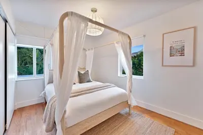 a bedroom with a canopy bed and two windows at Stunning Historic Villa with Jacuzzi Heated Pool and Resort style Backyard in Miami