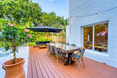 a wooden table with chairs and an umbrella on a deck at Stunning Historic Villa with Jacuzzi Heated Pool and Resort style Backyard in Miami